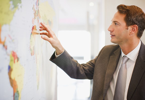 Man in suit looking at a world map.