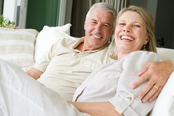 60-something couple sitting on a couch.