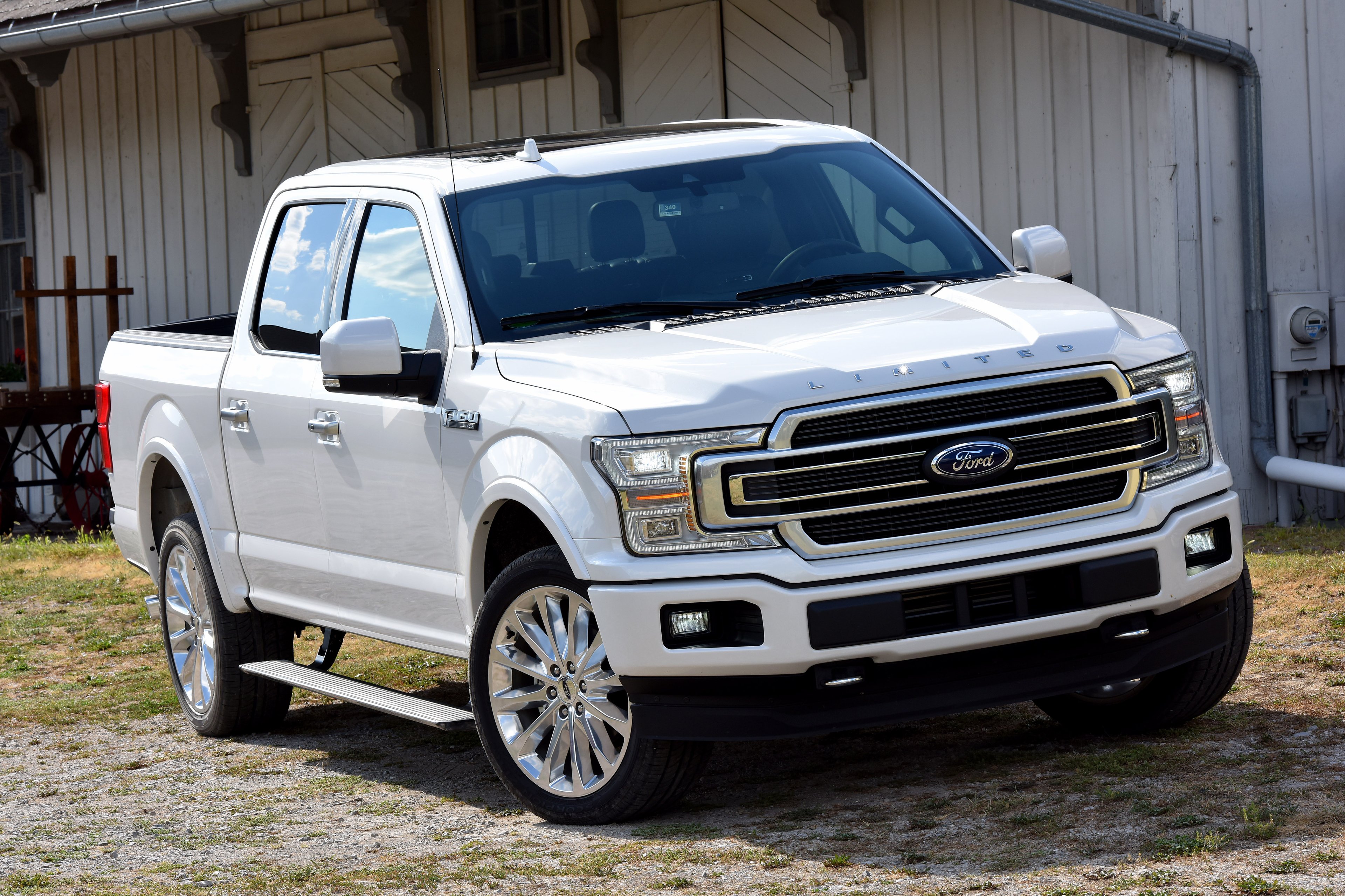 A white 2018 Ford F-150 Limited parked in front of a barn.
