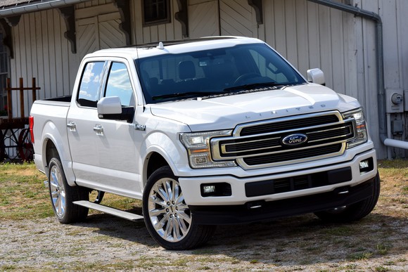 A white 2018 Ford F-150 Limited parked in front of a barn.