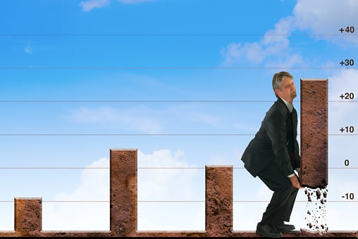 Picture of a bar graph with a man in a suit lifting the most recent bar up to reflect growth.