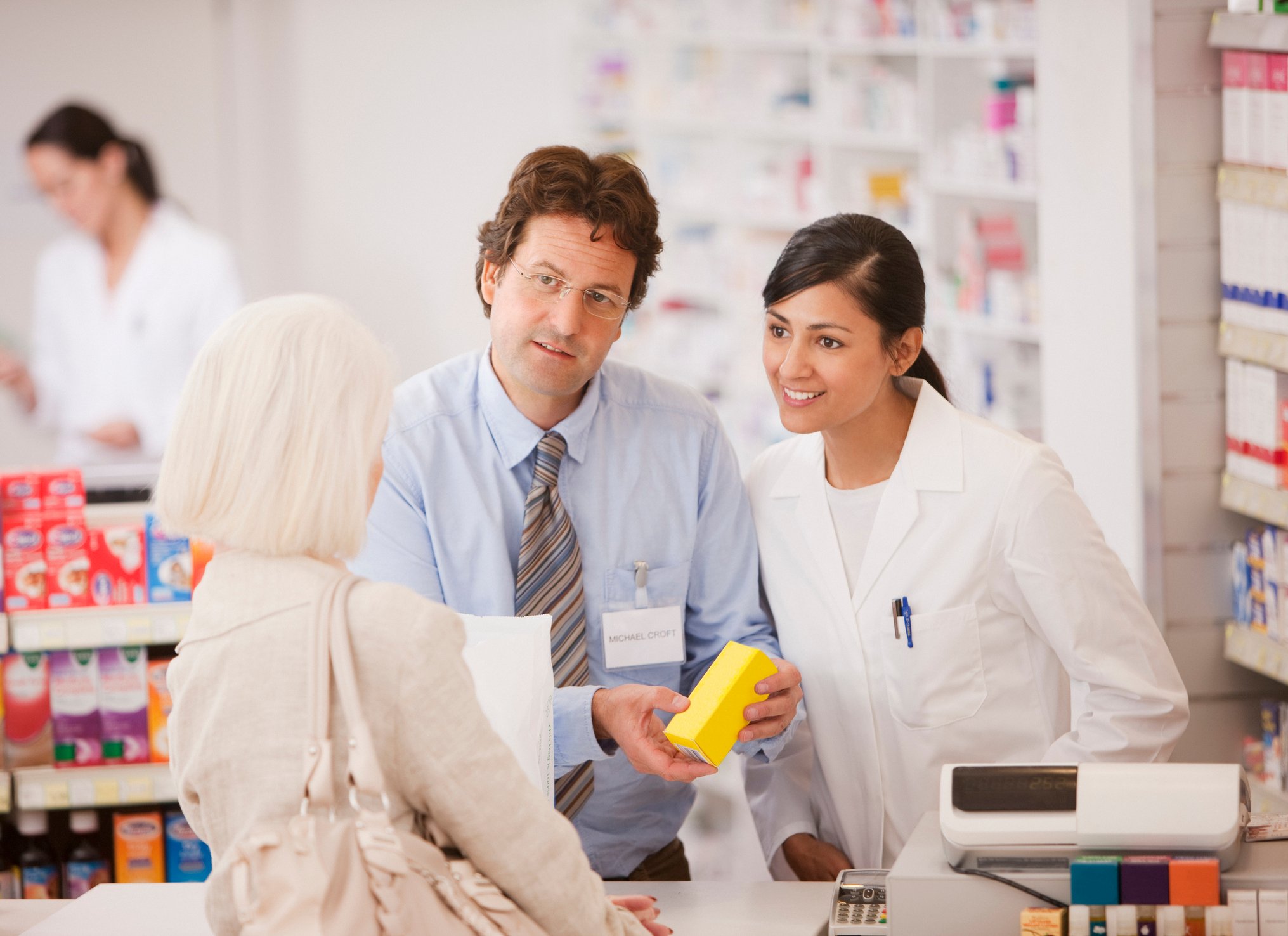 Pharmacists talking to shopper in drug store