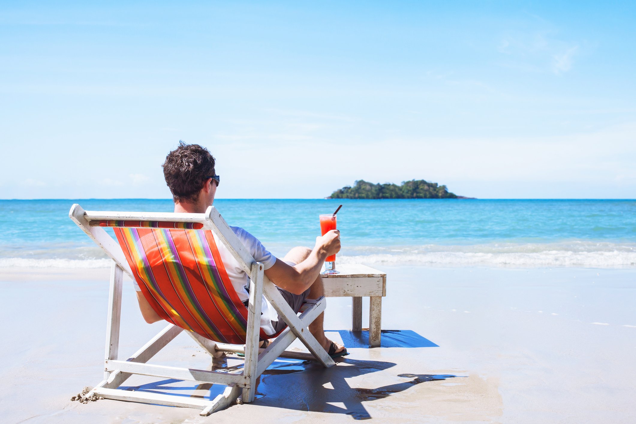 Man sitting on a beach chair facing the ocean