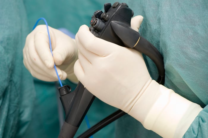 Gloved hands holding an endoscope.