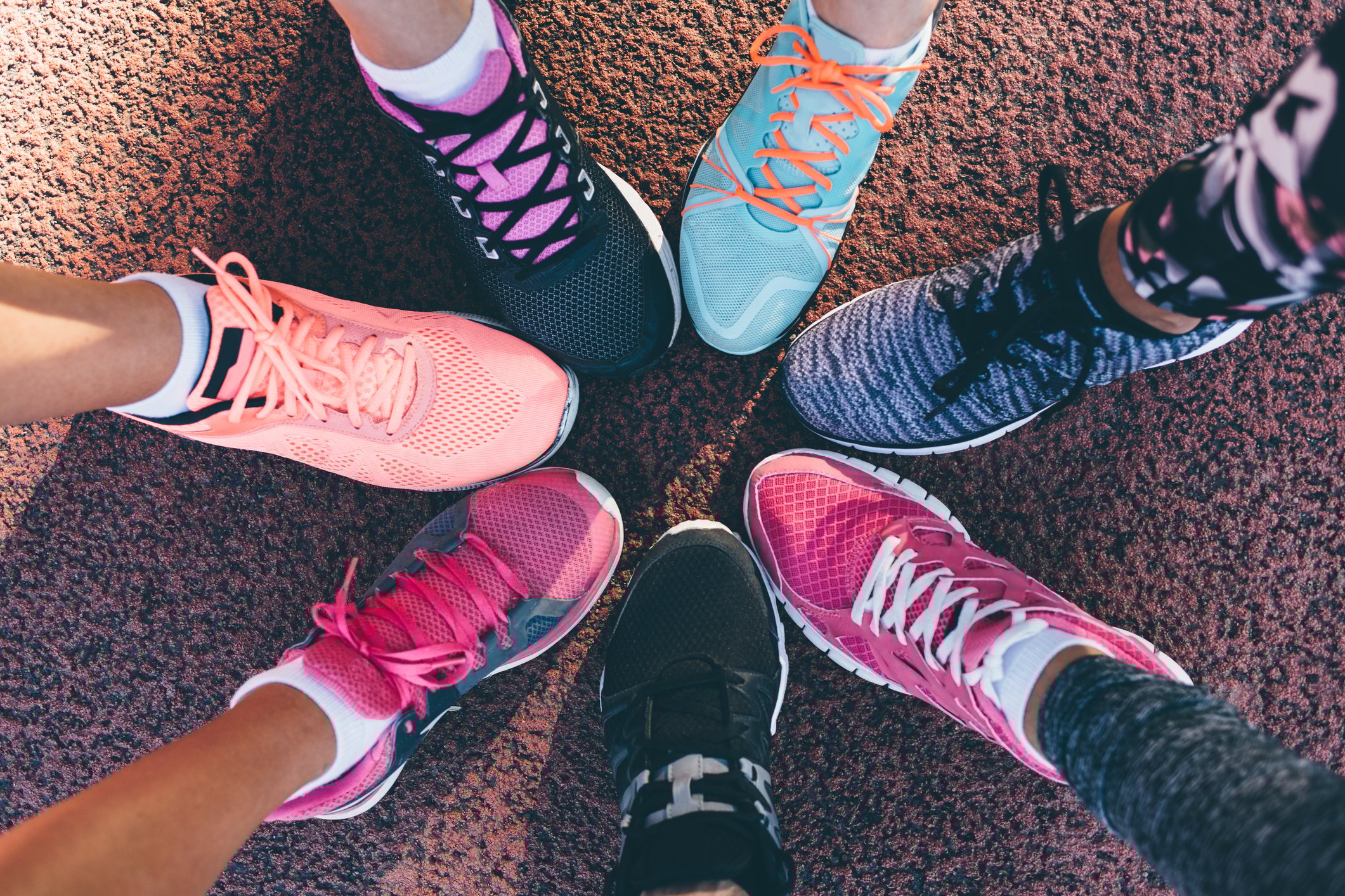 Seven people's legs arrange in a circle to show off their athletic shoes