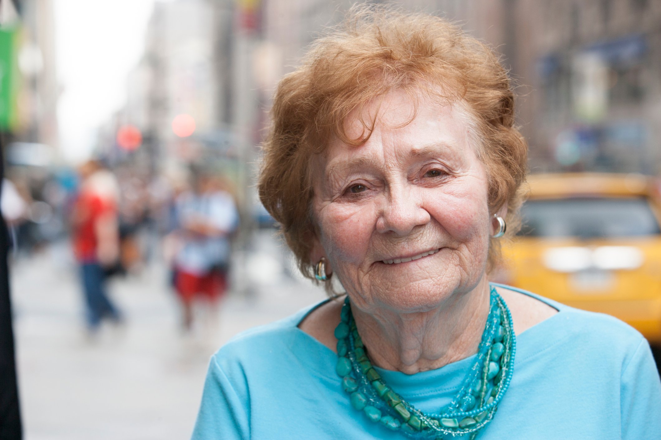 Senior woman on a city street with a taxi in the background