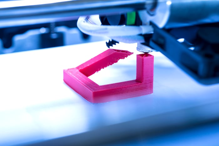 Close-up of 3D printer printing a fuschia-colored plastic object. 