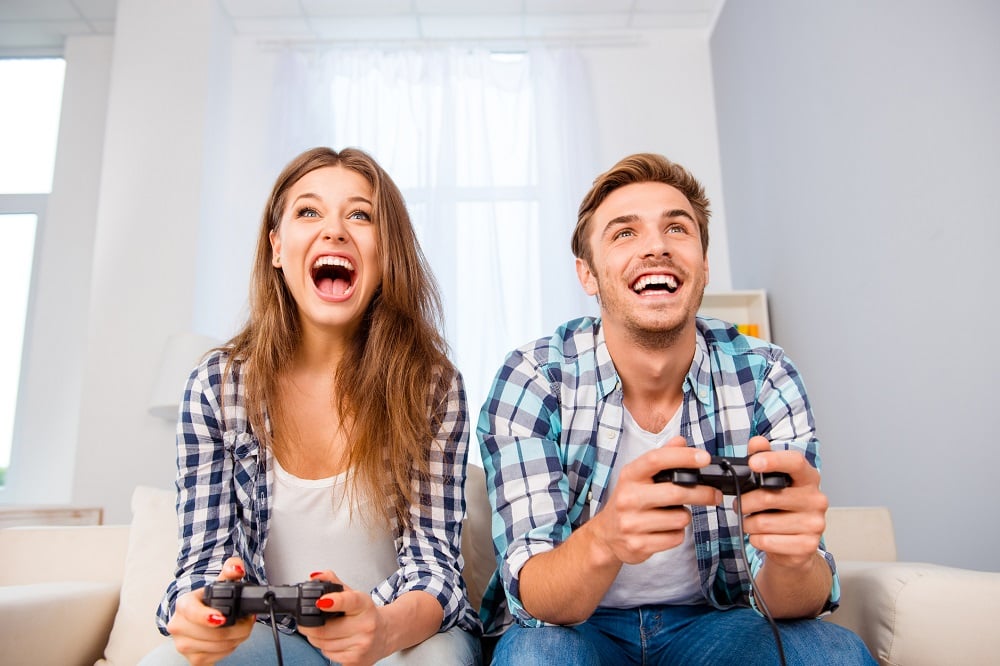 Happy young man and woman playing video games. 