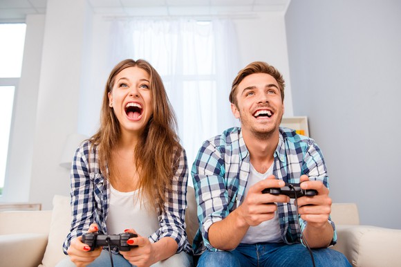 Happy young man and woman playing video games. 