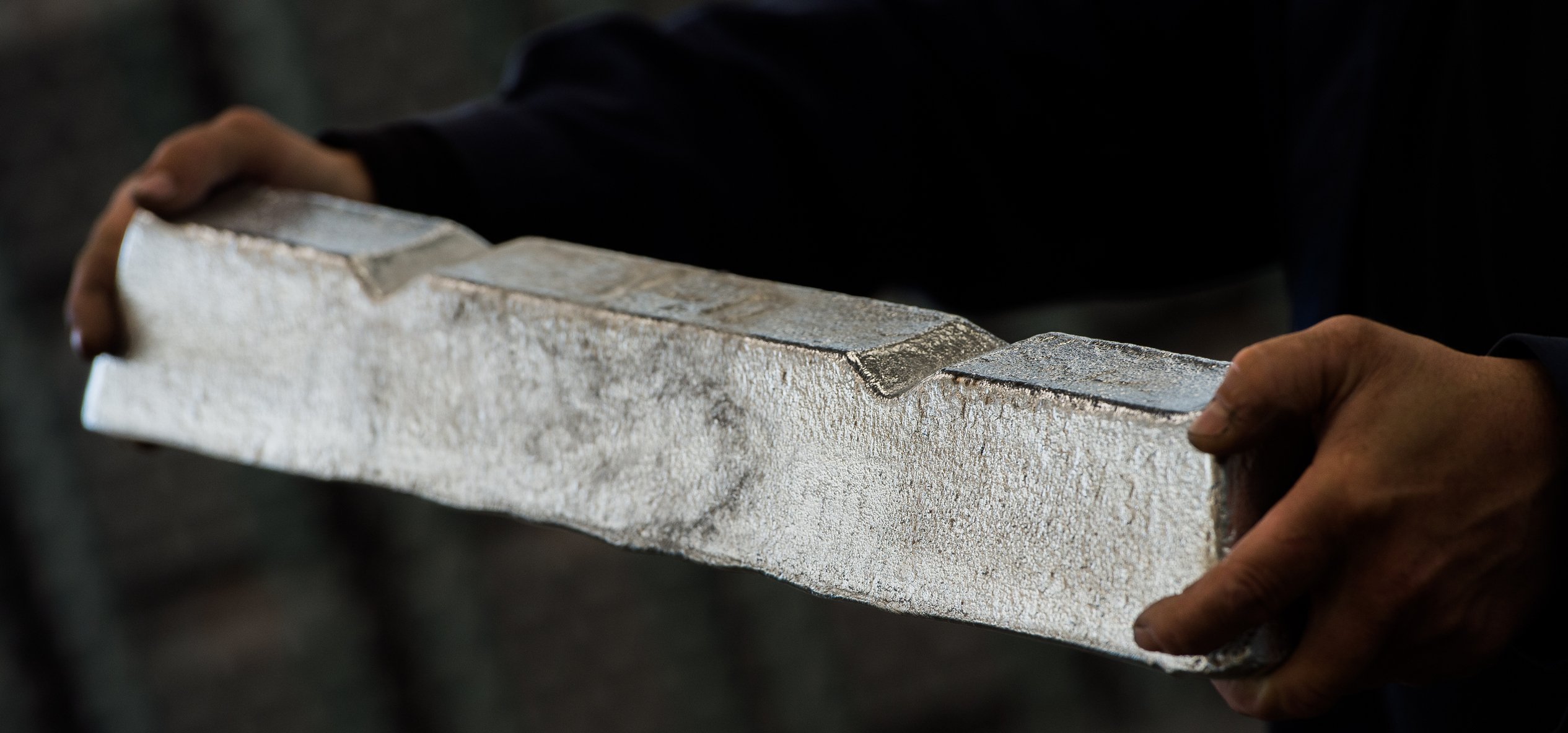 Someone holding a bar of raw aluminum.