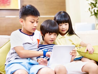Asian brothers and sister staring at a tablet