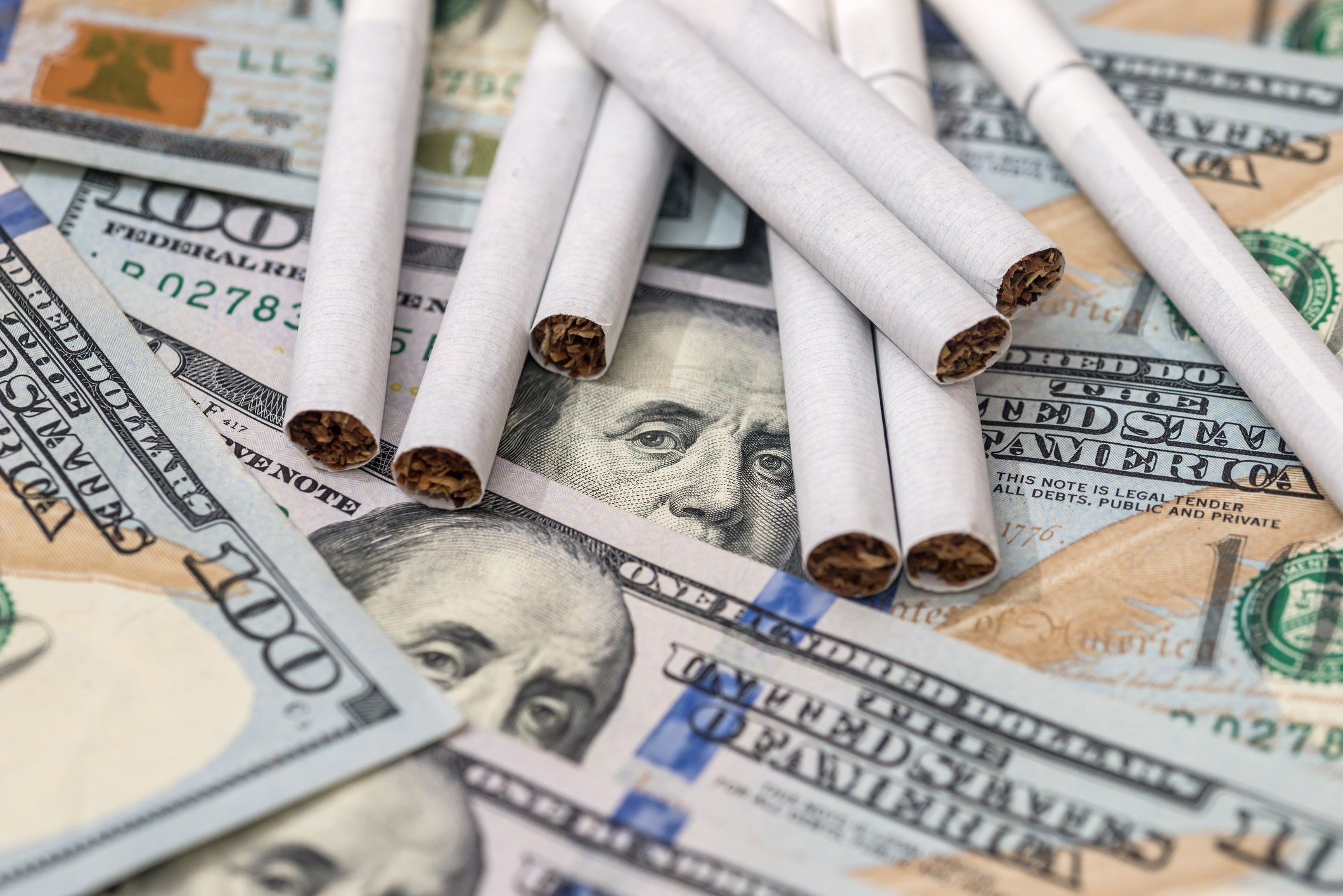 Cigarettes laying on top of $100 billis