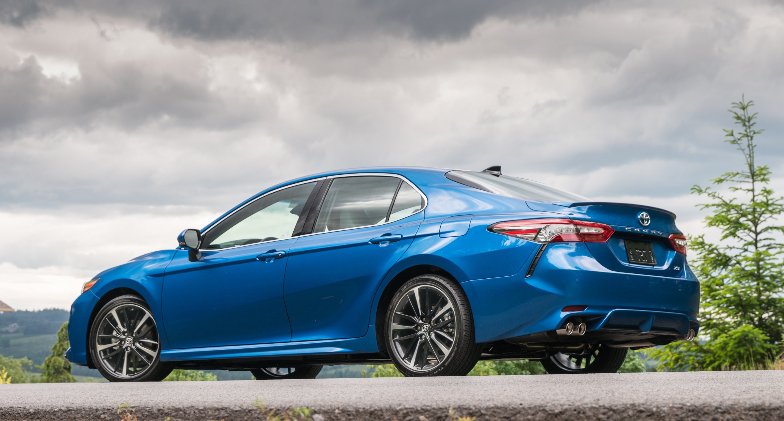 A blue 2018 Toyota Camry XSE, parked on a hill.