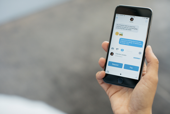 Hand holding smartphone displaying Apple's iMessage app with Venmo integration.