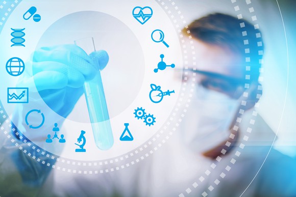 Scientist with surgical mask holding test tube with medical icons in foreground