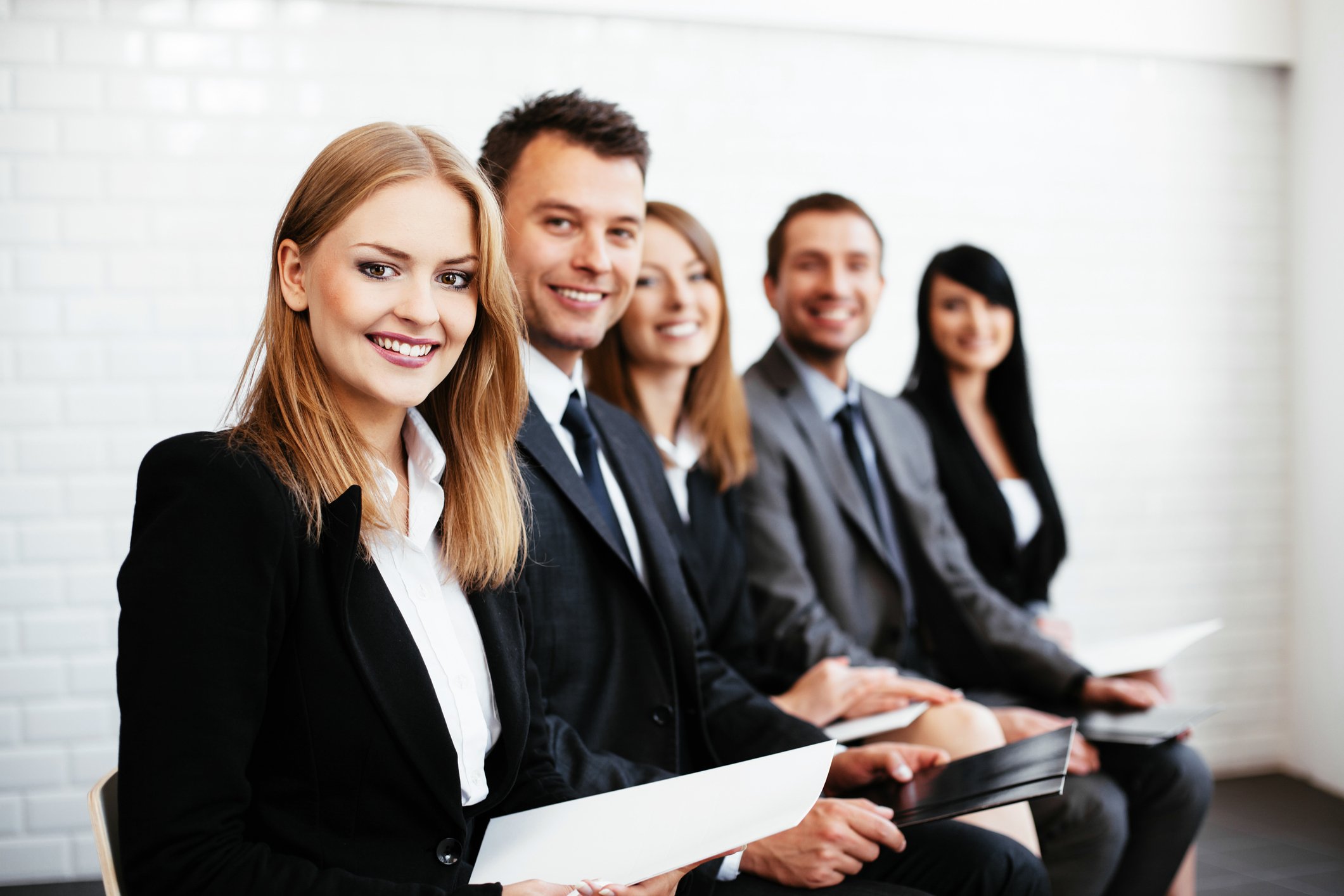 A group of people in suits lined up holding papers