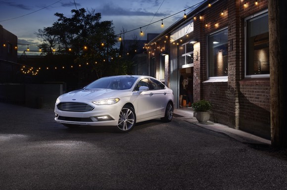A white Ford 2017 Fusion parked in front of a brick building at night