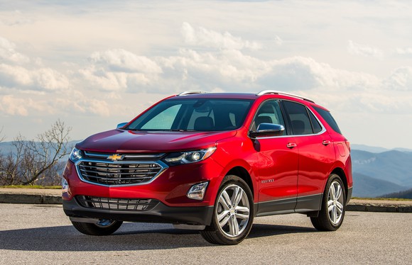 A 2018 Chevrolet Equinox in Cajun Red, parked outside with mountains in the background.