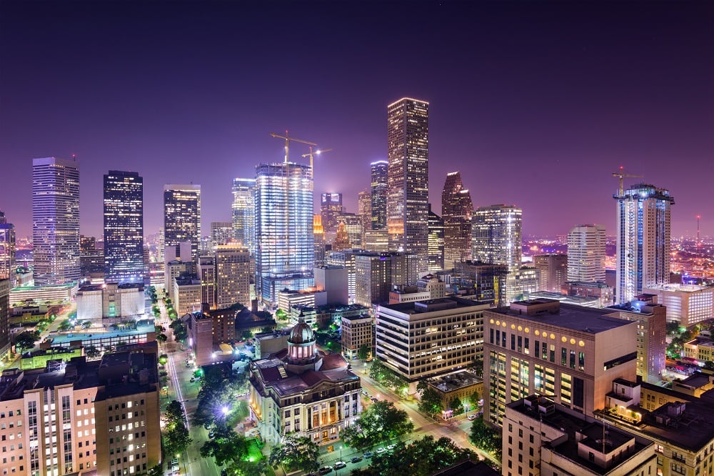 City skyline at night, showing multiple large construction cranes.