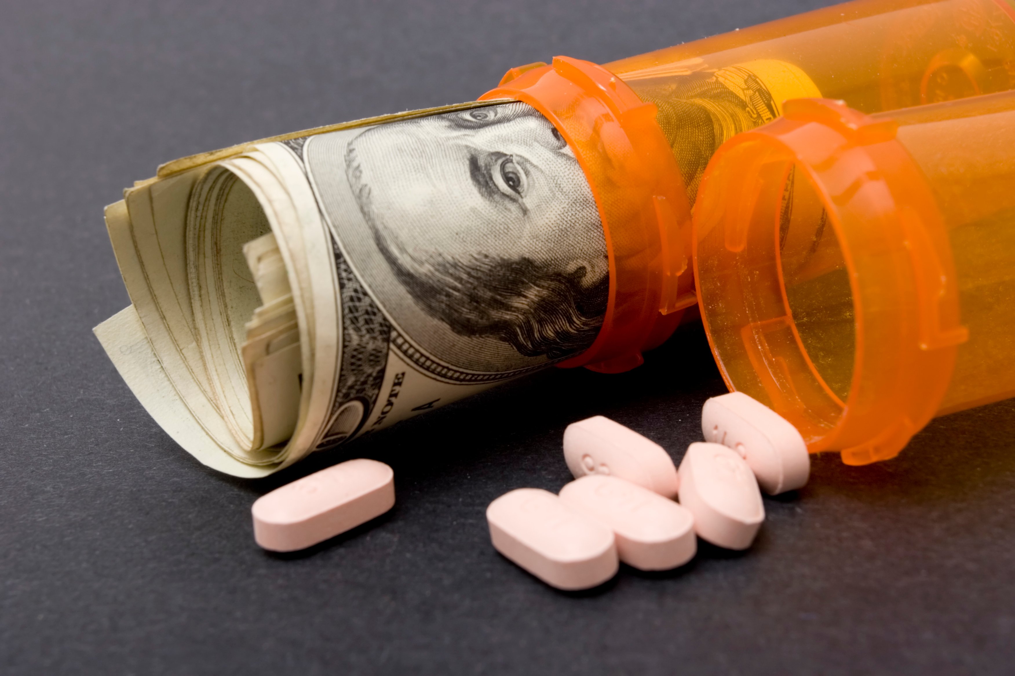 Pills and pills bottle with $100 bills in bottle