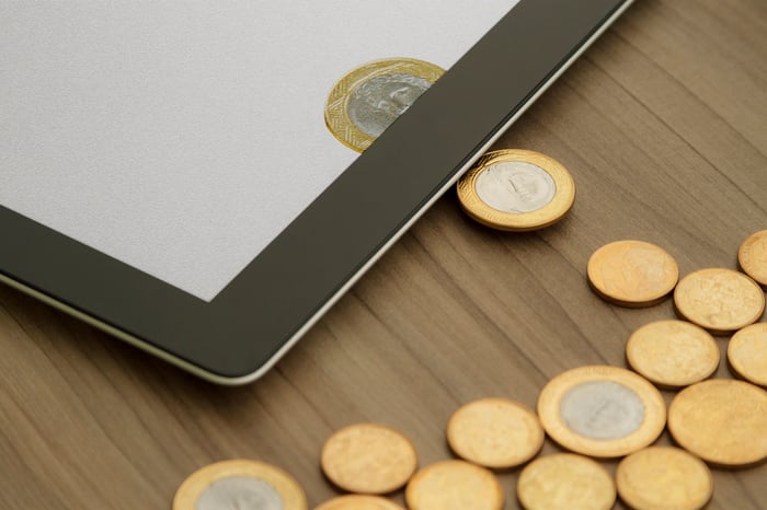 Physical coins turning into digital coins on a tablet. 