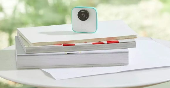 A Google Clips camera sitting on a stack of books.