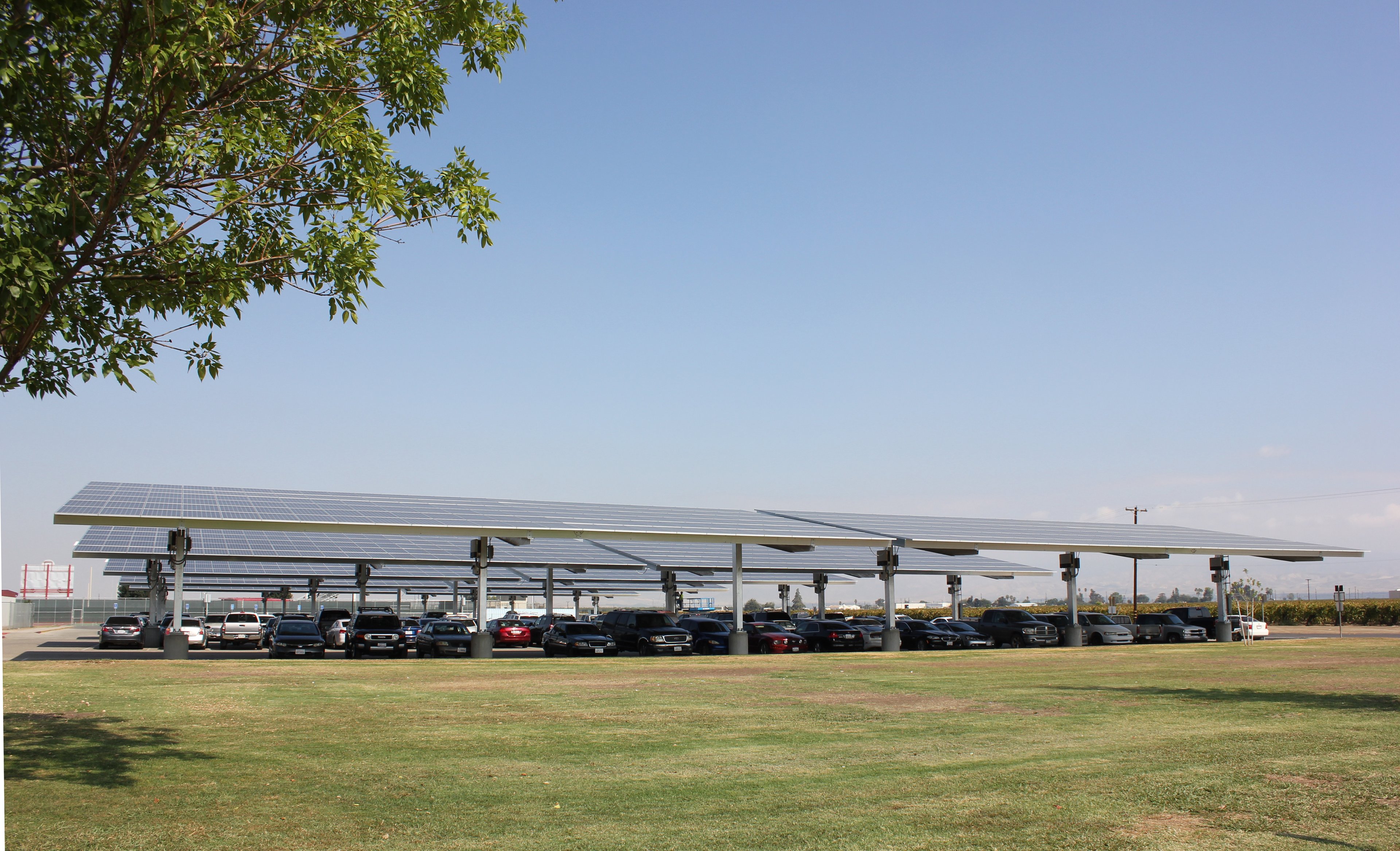Solar carport with cars underneath on a sunny day. 
