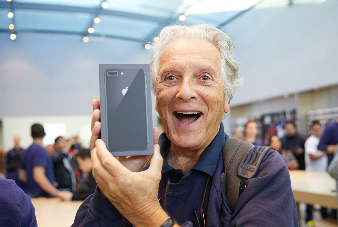 A smiling man holding a new iPhone 8 Plus.