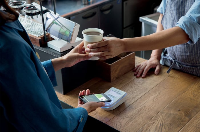 A woman uses Apple Pay to buy a coffee.