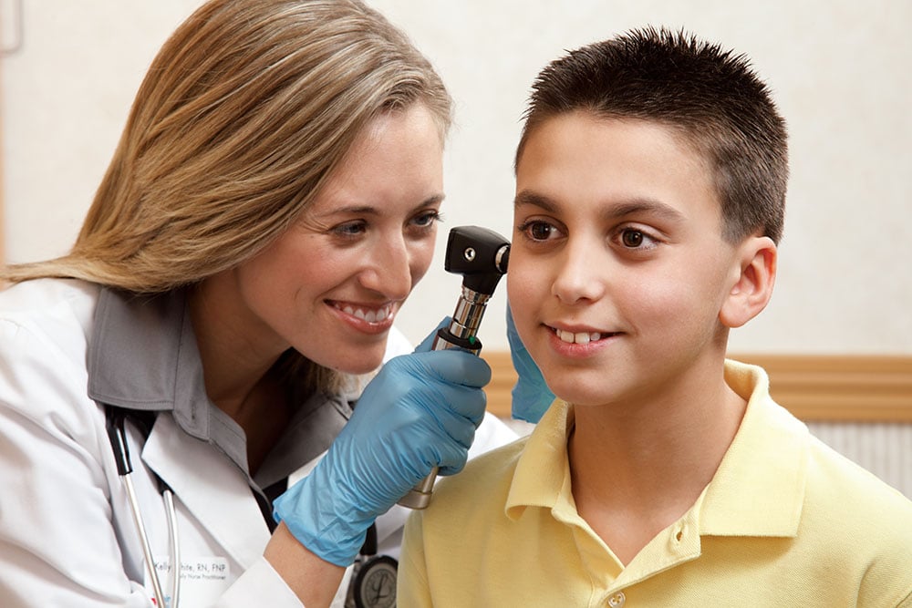 Doctor looking into patient's ear in clinic.