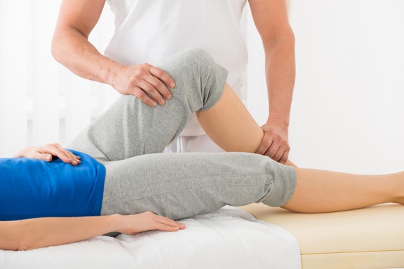 Physical therapist stretching patient's leg