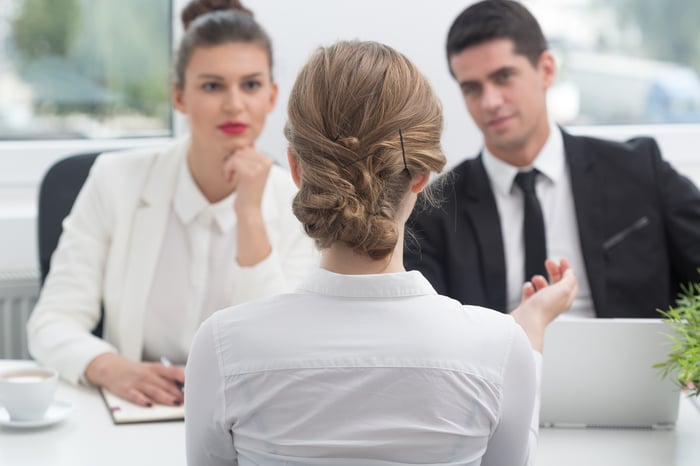 A man and a woman interview a woman at a table.