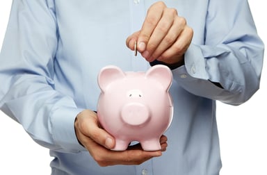Male hand putting coin into a piggy bank