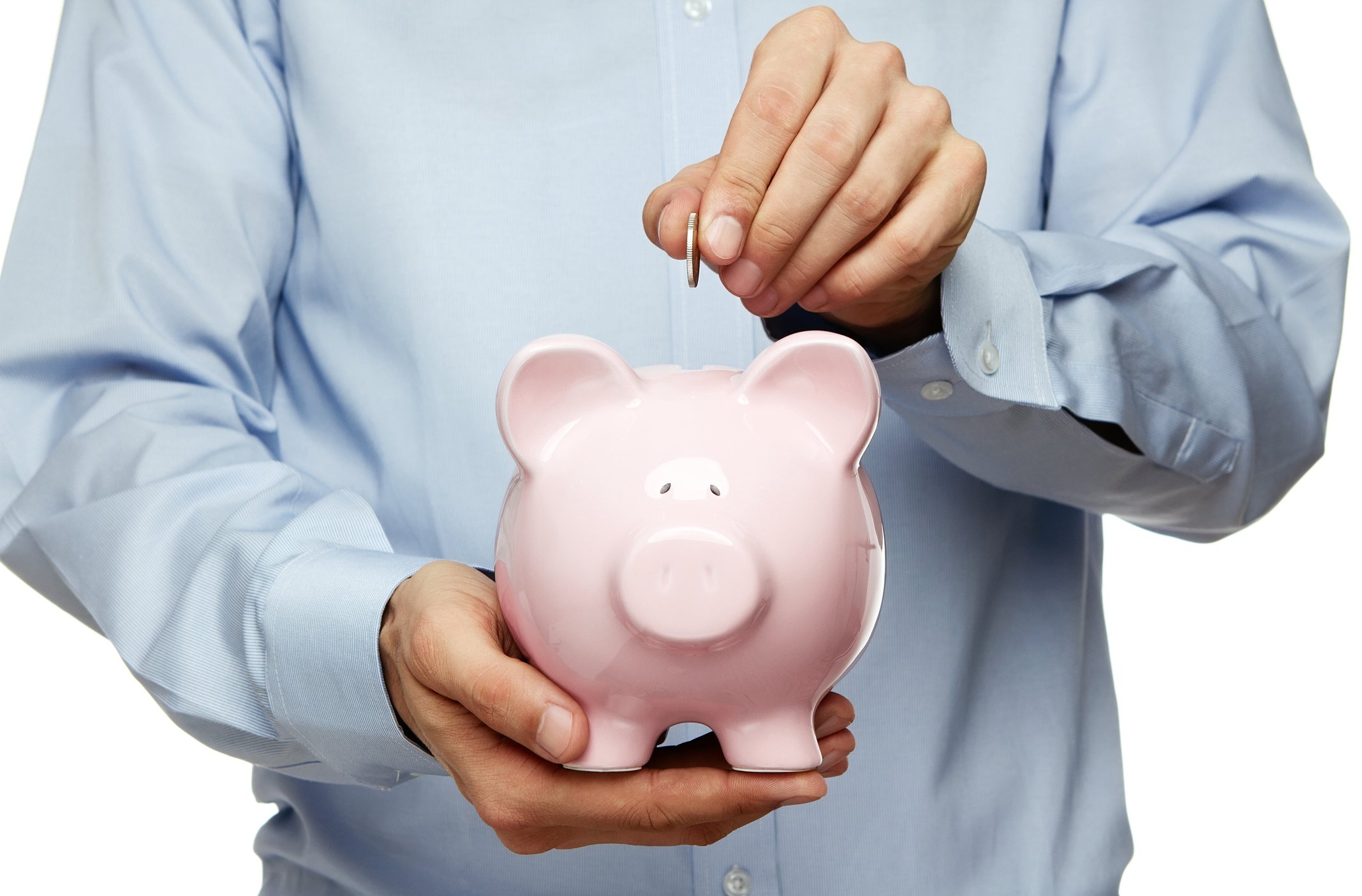 Male hand putting coin into a piggy bank.
