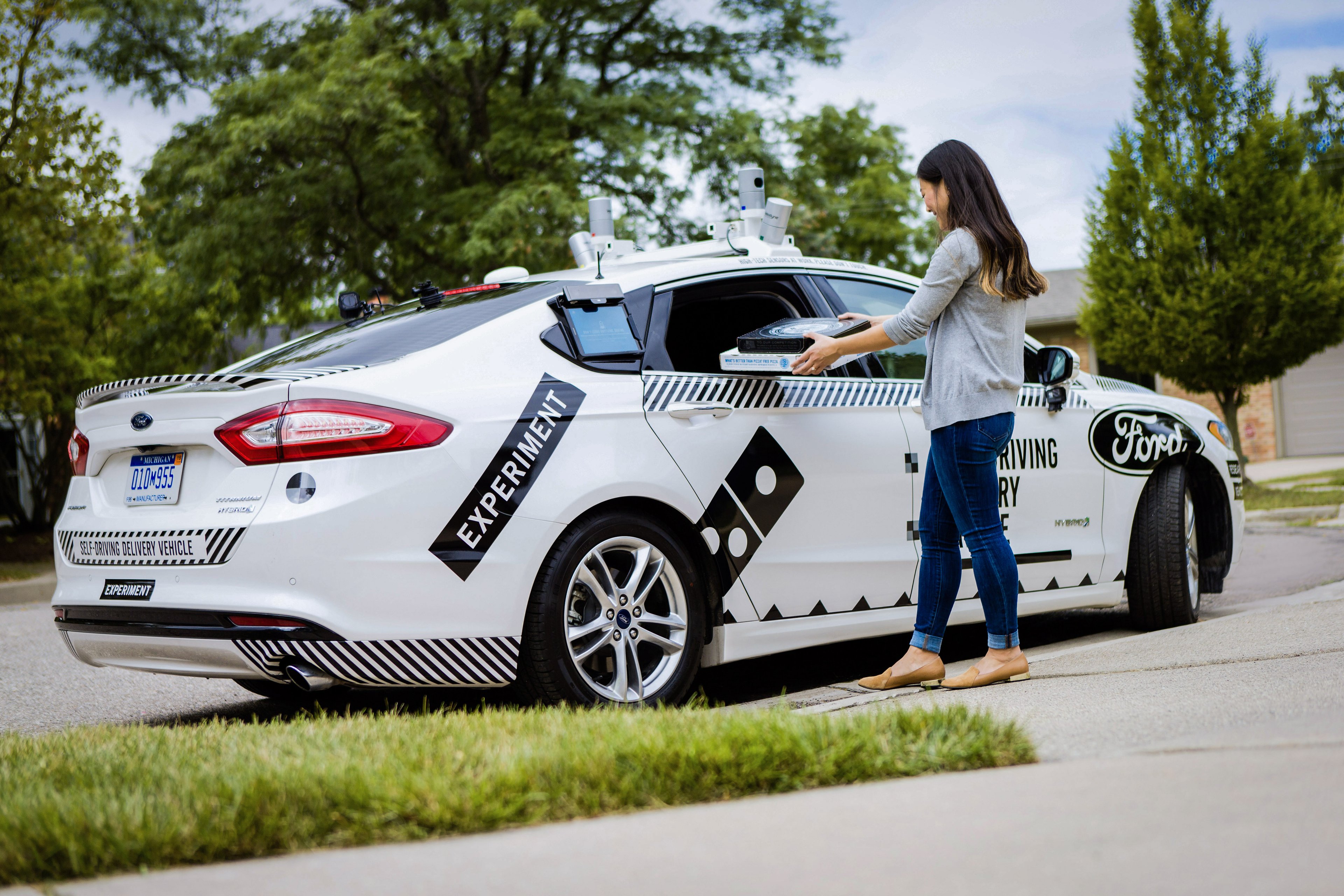 Ford's Fusion with autonomous vehicle technology delivering a pizza to a woman