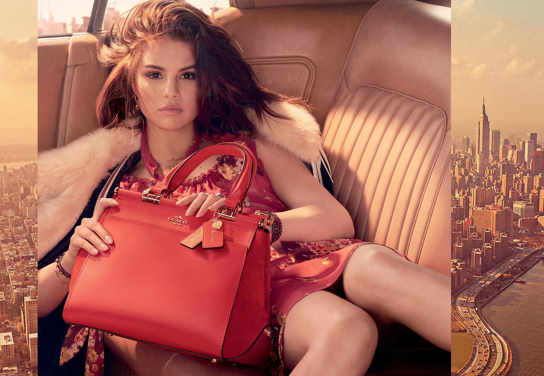 A woman sitting in the backseat of a car holding a red leather Coach handbag.