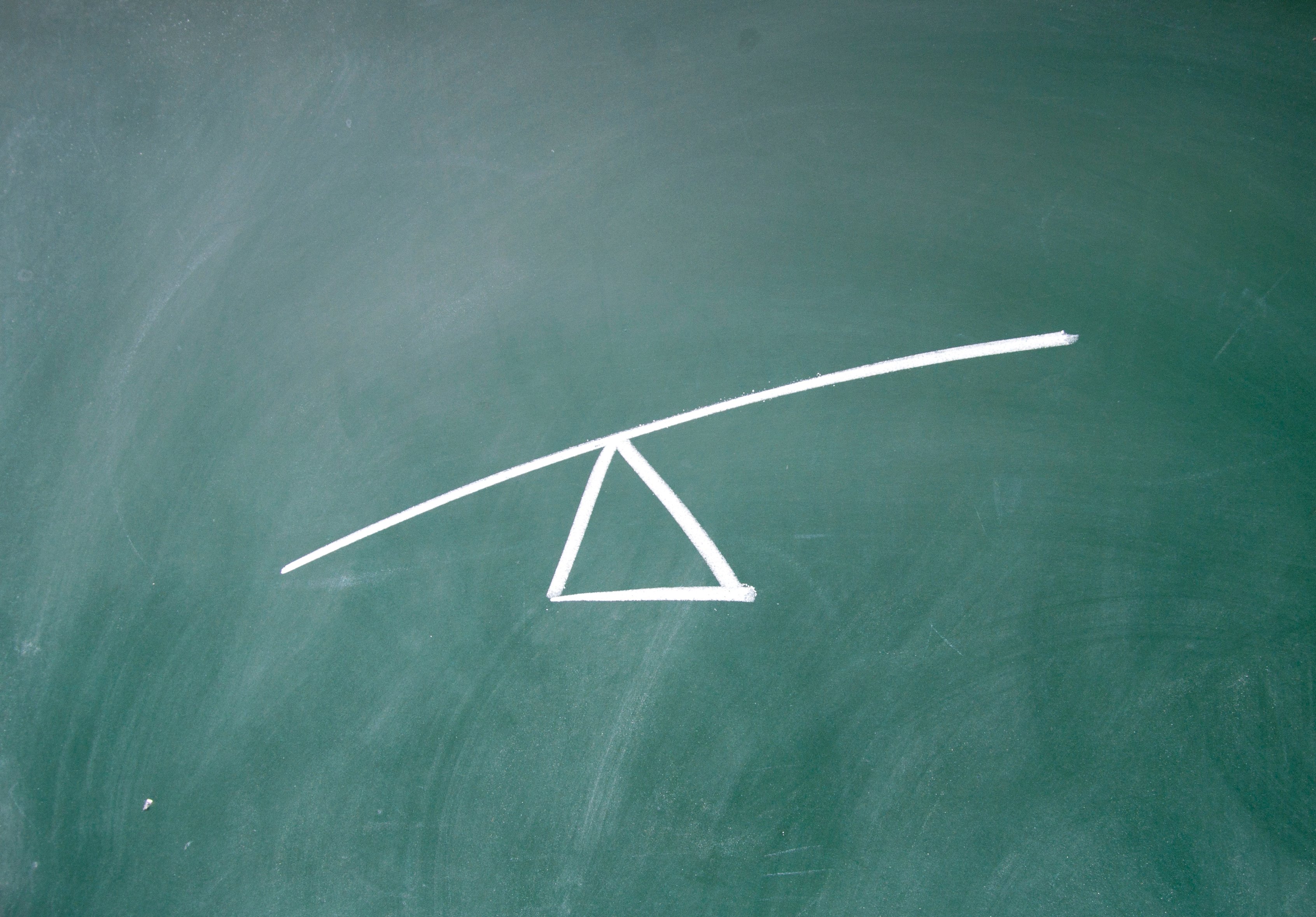 A drawing on a chalkboard of a triangle with a line balanced on top, meant to demonstrate leverage.