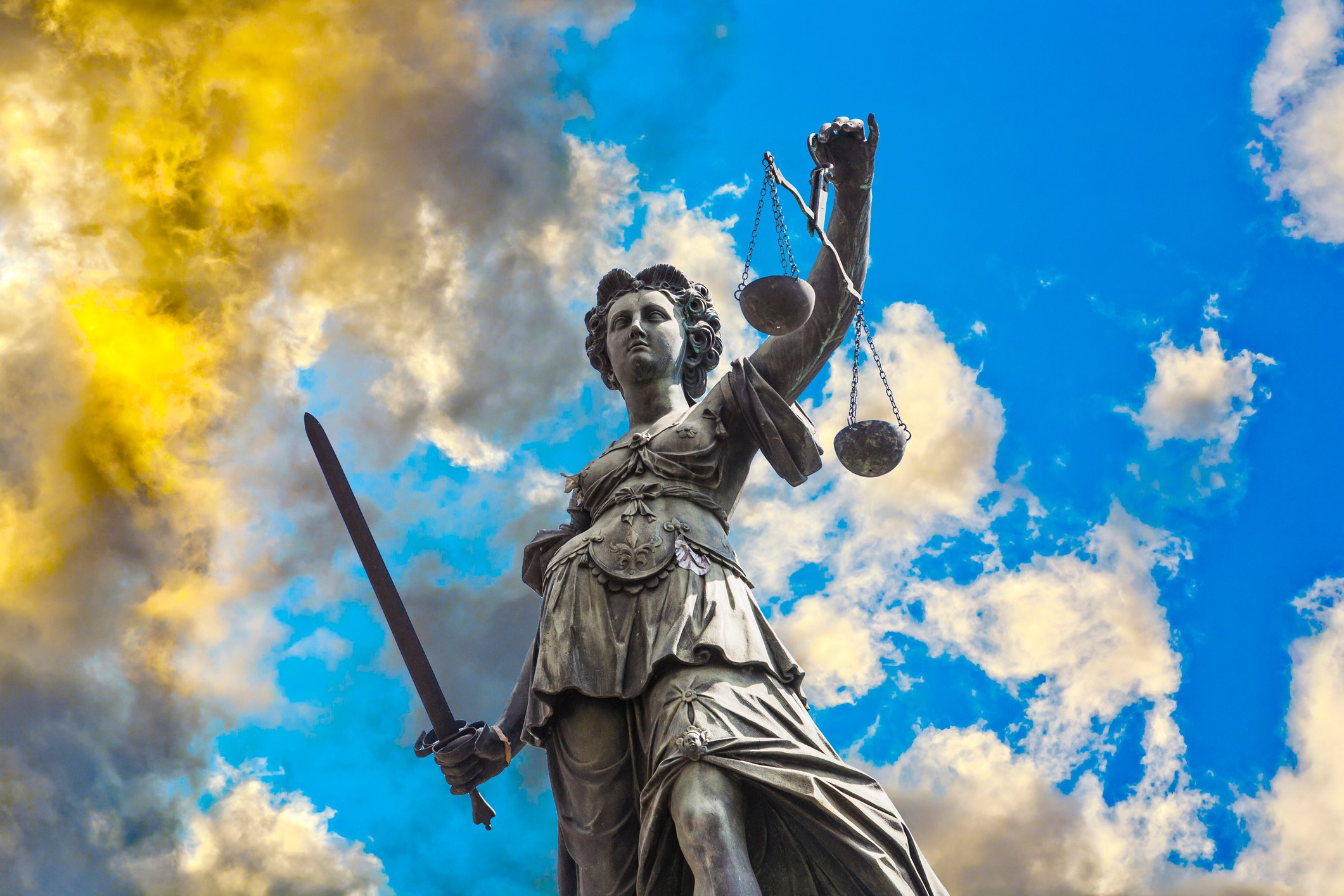 A statue of Lady Justice, set against swirling clouds.