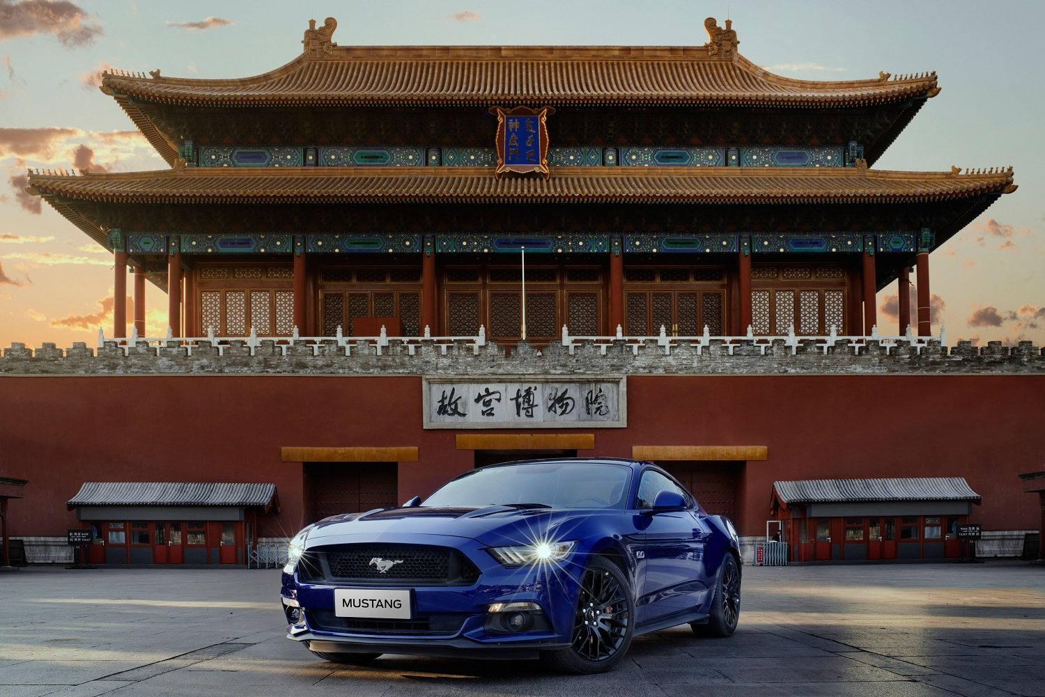 A blue Ford Mustang in front of a traditional Chinese building.
