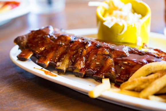 Baby back ribs on white dinner plate with fries