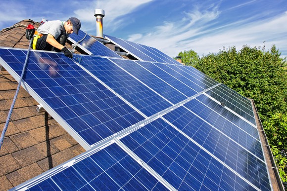 Installer putting solar panels on a home rooftop.
