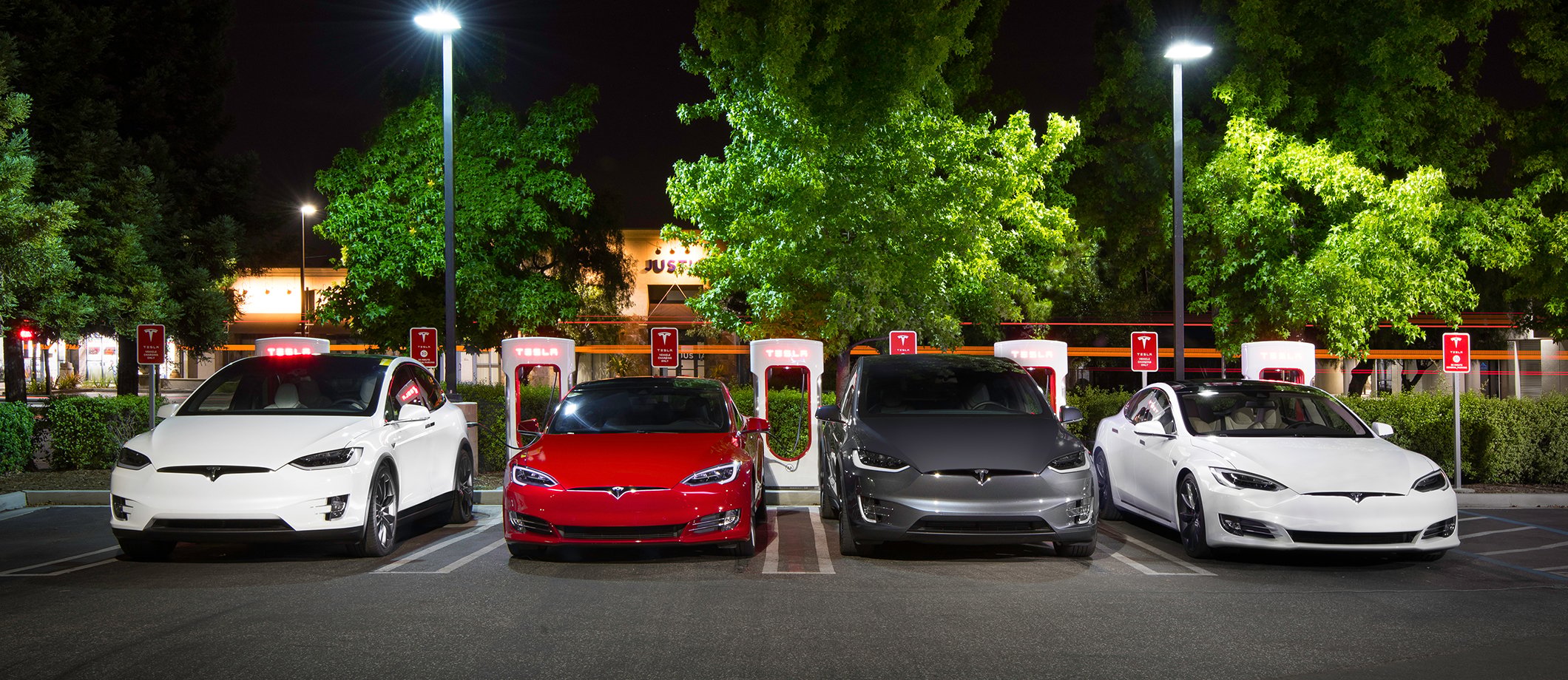 Four Tesla cars charging at a Supercharger station