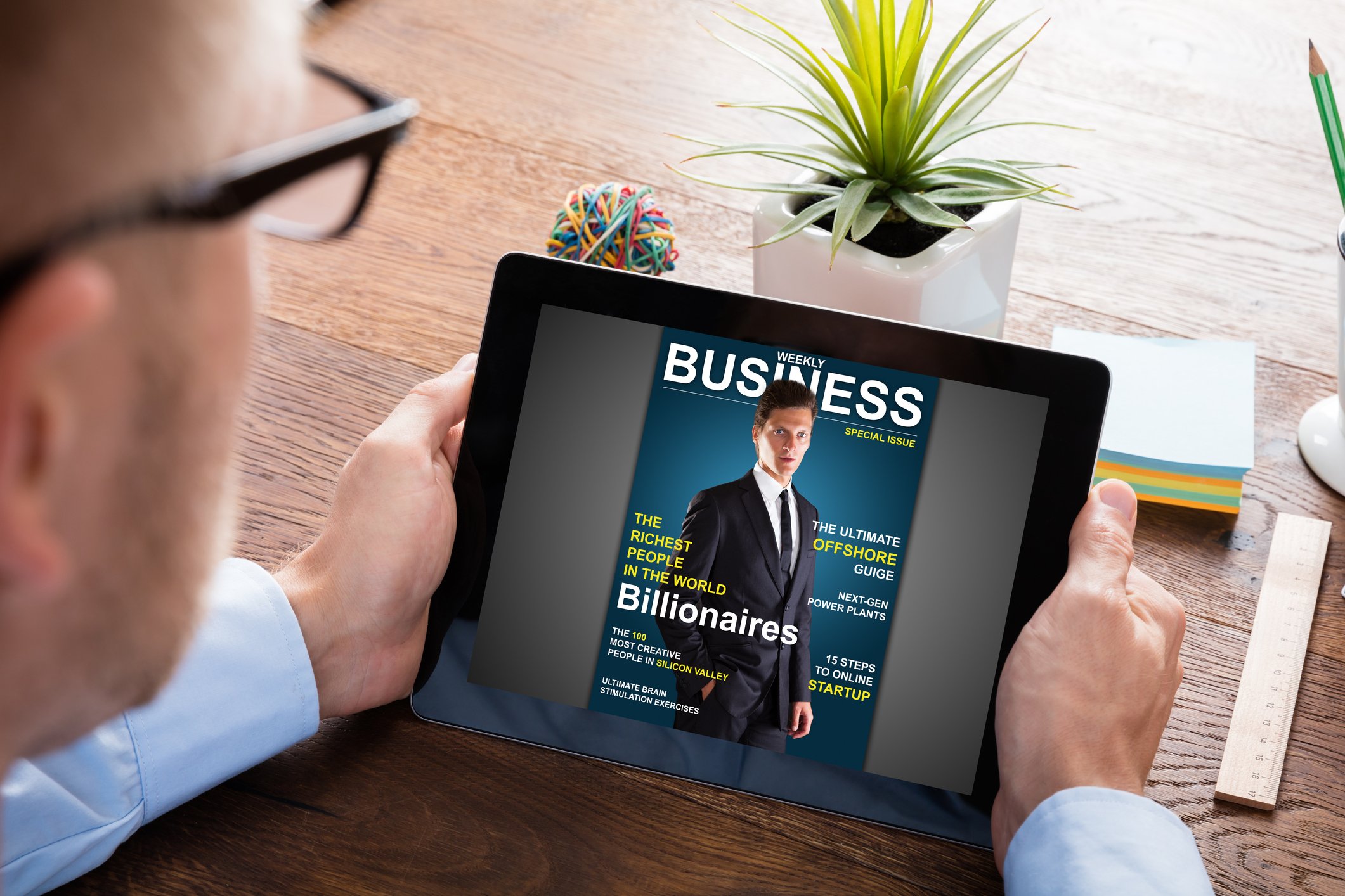 Man looking at tablet with cover of online business magazine. 