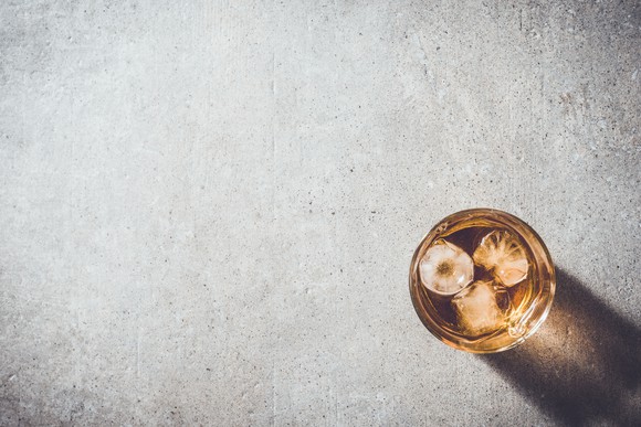 An overhead view of a glass of whiskey sitting on a table.