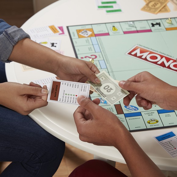 Monopoly game player exchanging a property card for cash.