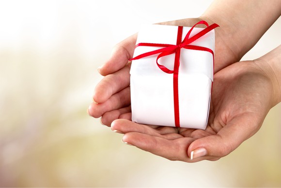 A person with cupped hands holding a wrapped present.
