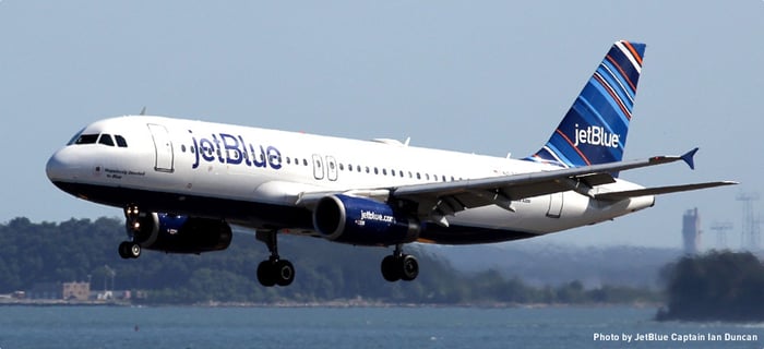 A JetBlue Airways plane about to land, with water in the background