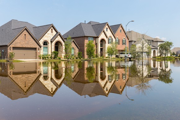 A row of houses with flooding across the street and up to the houses