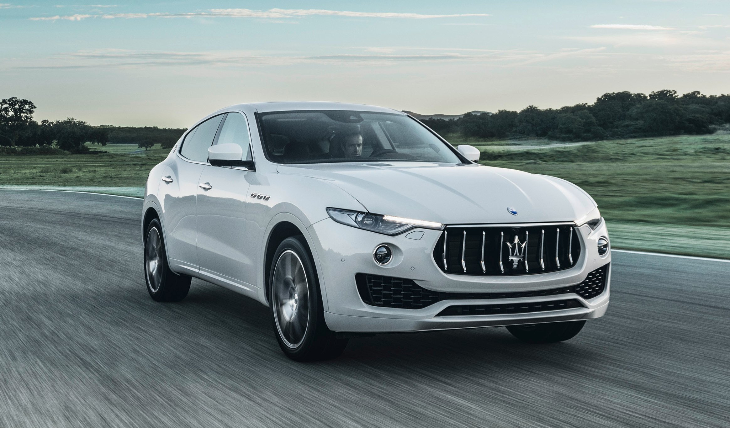 A white Maserati Levante, a midsize luxury SUV, on a country road.
