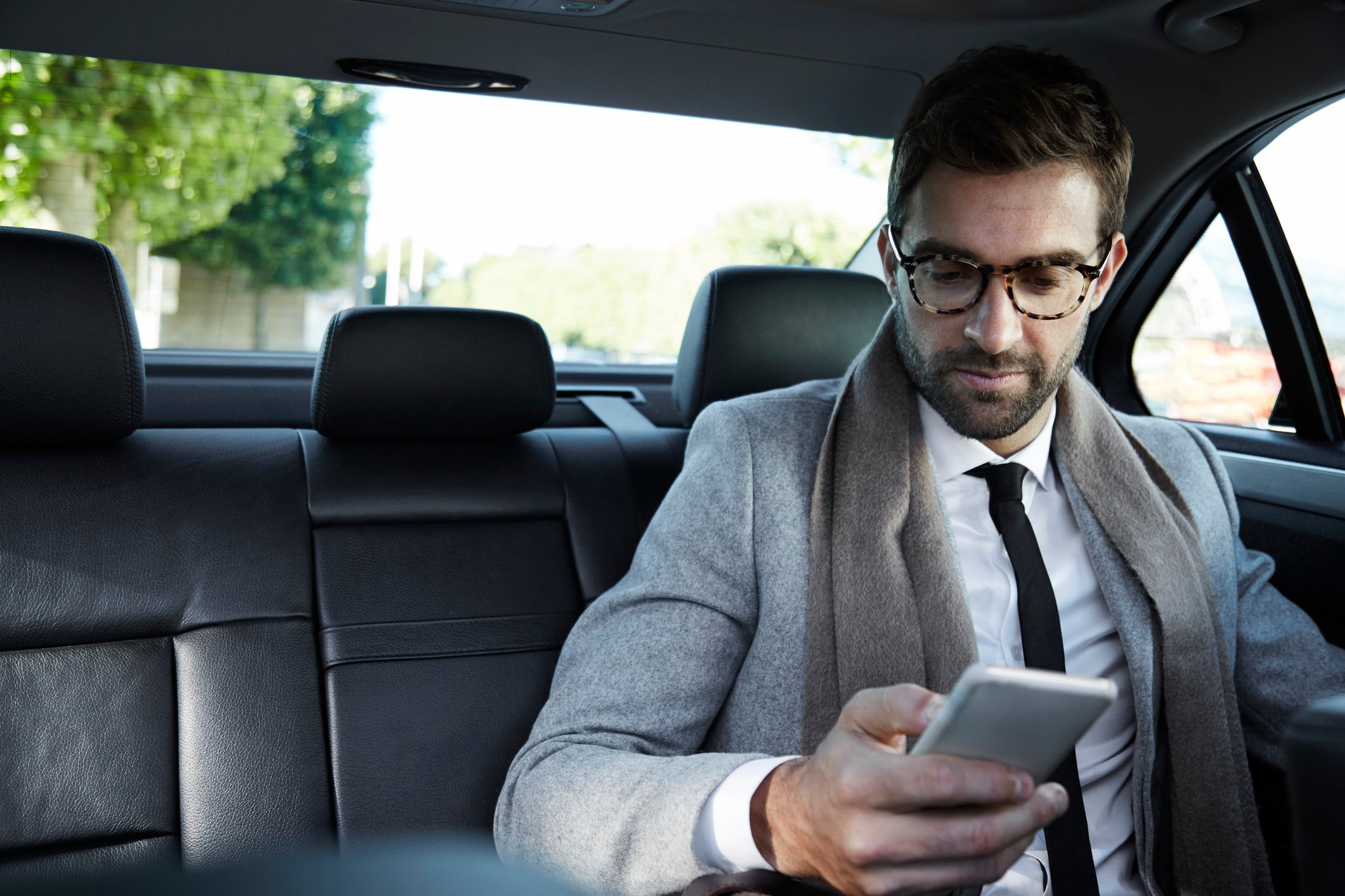 A businessman using his smartphone in the back of a cab